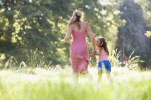 Woman and young girl running outdoors holding hands and smiling